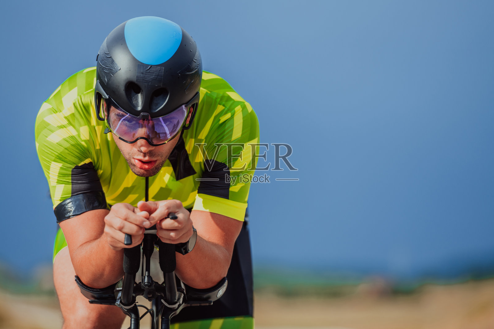 一个穿着运动服、戴着防护头盔骑自行车的铁人三项运动员的全身画像。有选择性的重点照片摄影图片