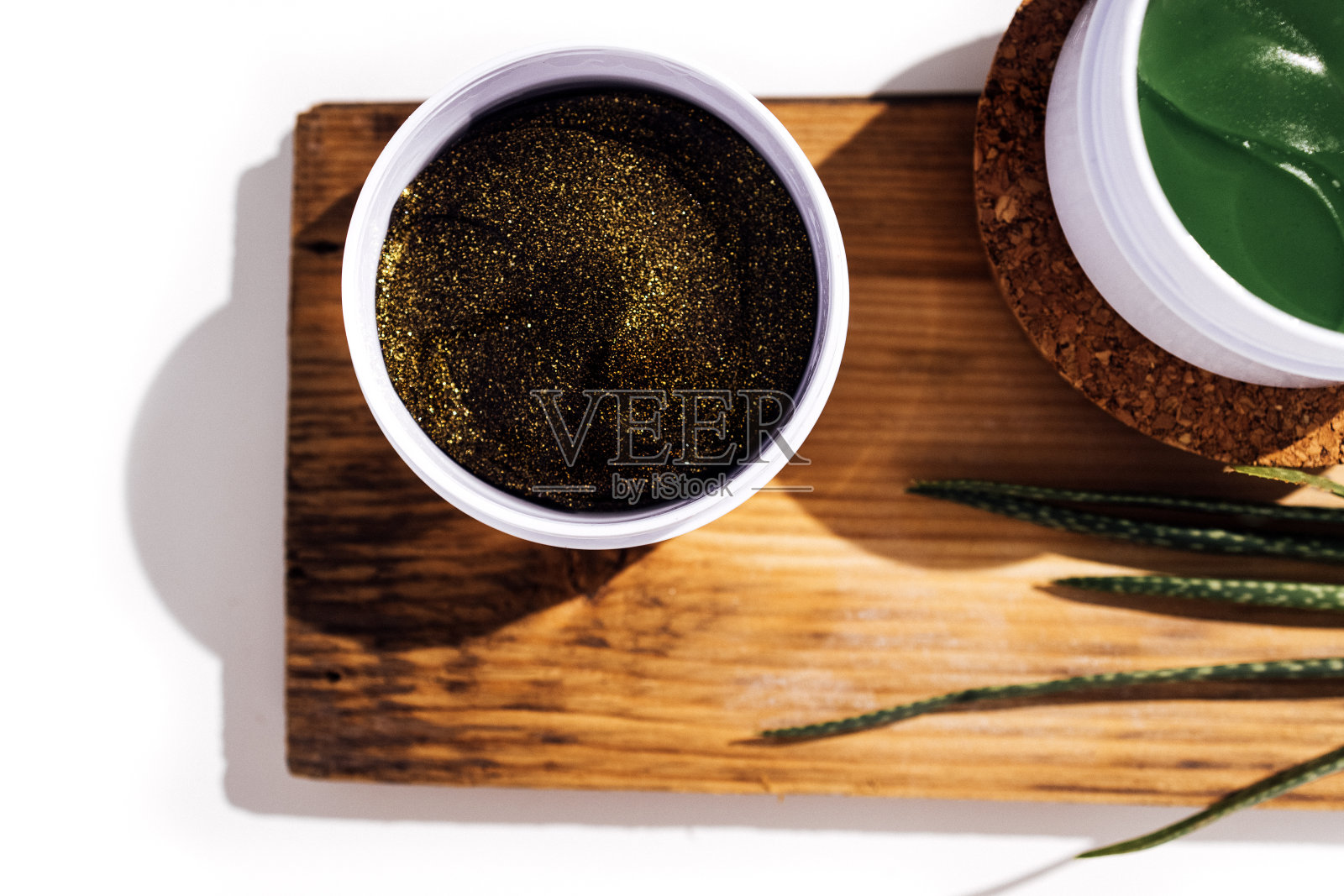 塑料罐与绿色胶原蛋白眼罩在软木阶段。芦荟植物，木形和胶原蛋白照片摄影图片