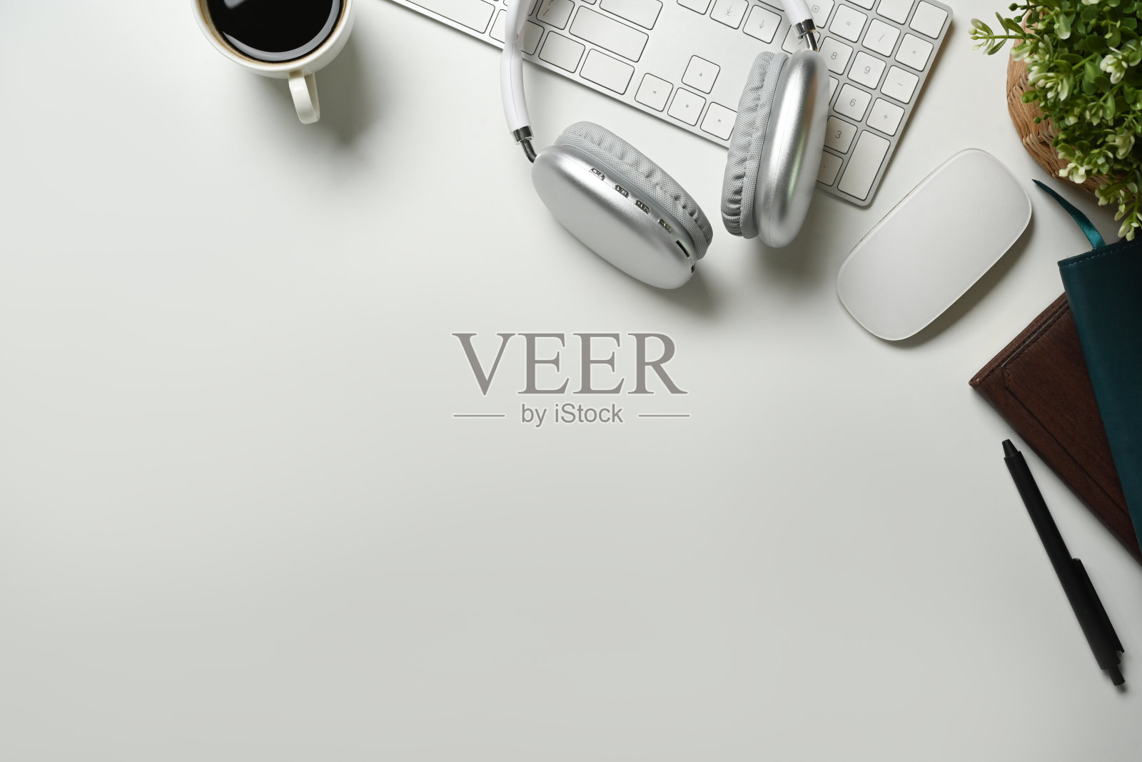 平躺着，白色办公桌上的无线耳机、咖啡杯和键盘俯视图。为你的文本复制空间。照片摄影图片