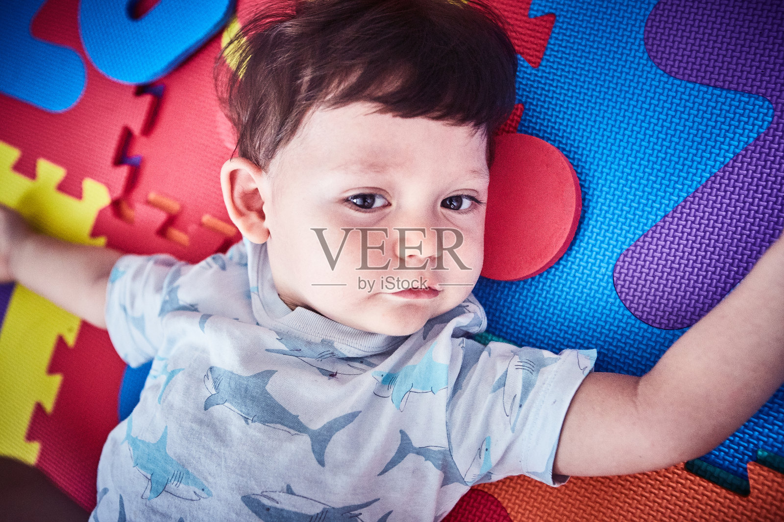 蹒跚学步的孩子躺在儿童游戏垫上照片摄影图片