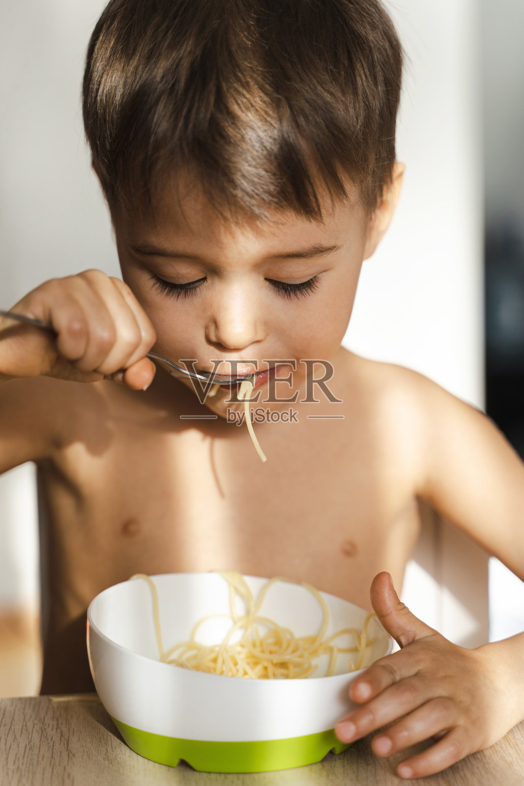 可爱的小男孩在吃他最喜欢的食物——意大利面照片摄影图片