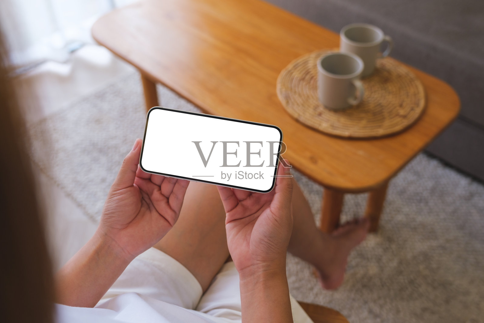 顶视图模型图像的妇女手持手机与空白桌面白色屏幕在家里照片摄影图片