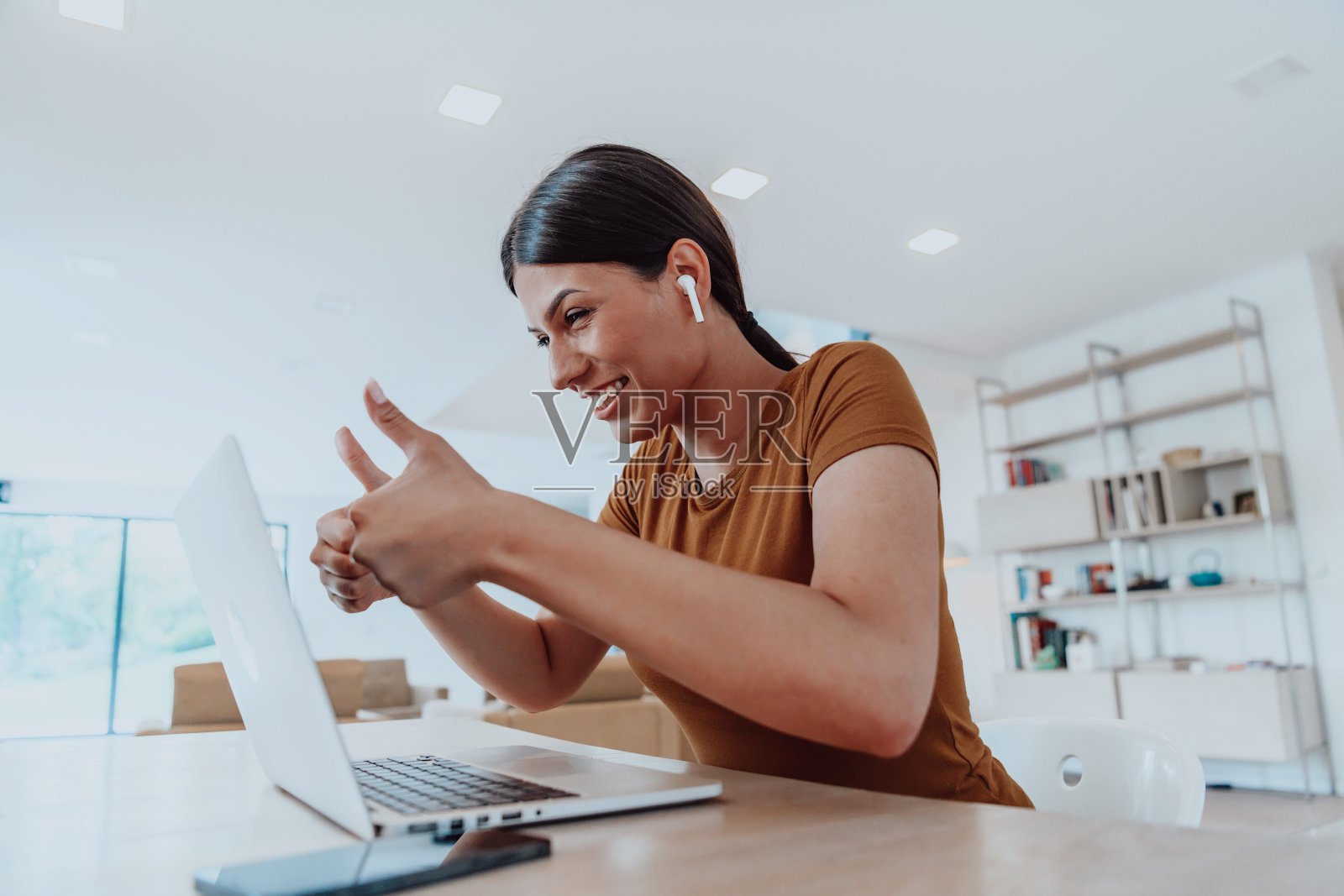 女人坐在客厅里，用笔记本电脑看摄像头，和生意上的朋友亲戚视频通话，拍大头。工作面试回答问题。照片摄影图片