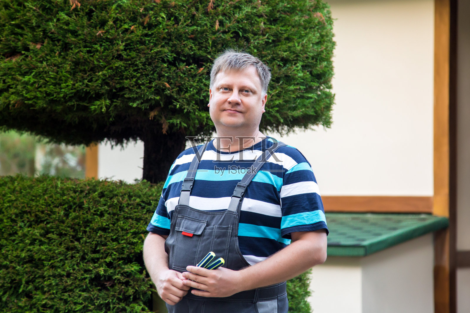 一个穿着工作服，手里拿着工具的人站在房子附近照片摄影图片