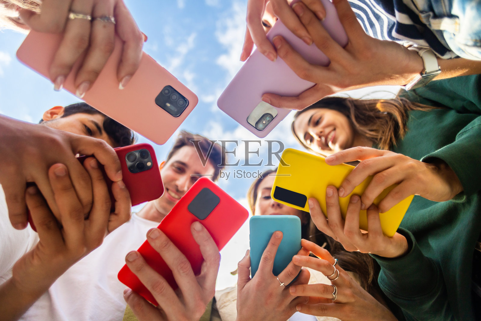 使用手机的年轻人在户外围成一圈站着照片摄影图片