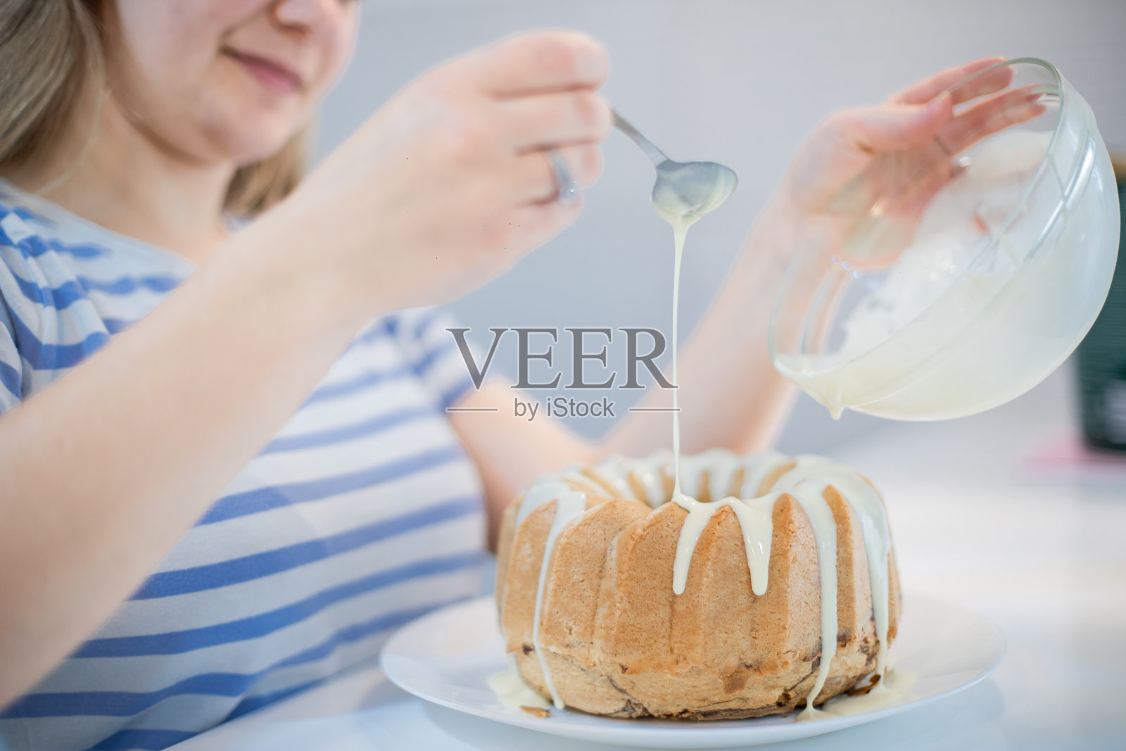 年轻女子正在装饰库格霍夫蛋糕，并把融化的白巧克力倒在上面照片摄影图片