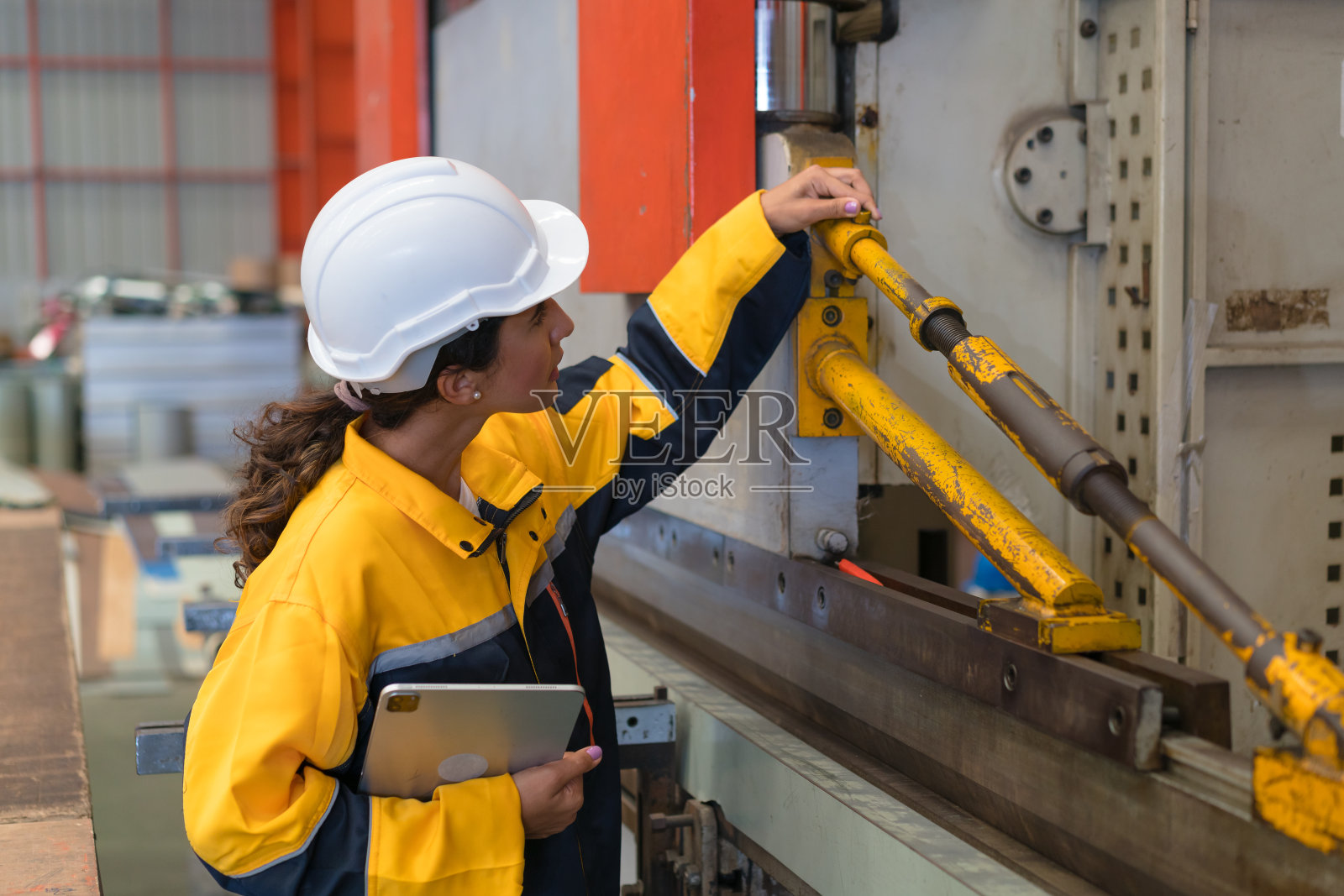 在金属制造仓库中穿着安全制服的专业重工业工程师，以安全第一的理念进行维修服务检查。照片摄影图片