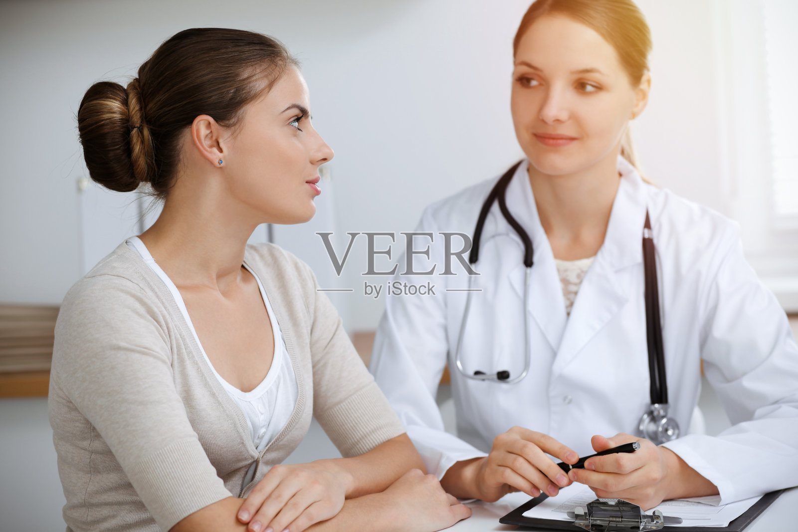 在阳光明媚的诊所里，医生和病人坐在一起讨论健康检查结果照片摄影图片