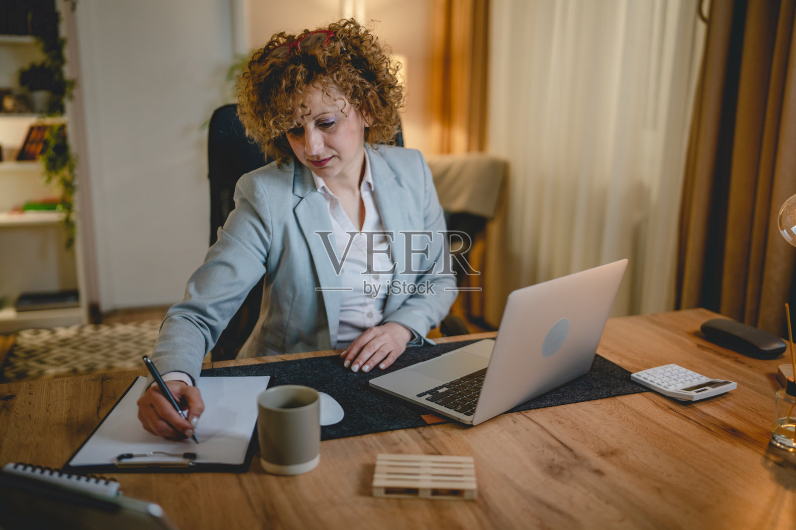 一个快乐的女人在家或办公室工作，坐在桌子旁使用笔记本电脑照片摄影图片