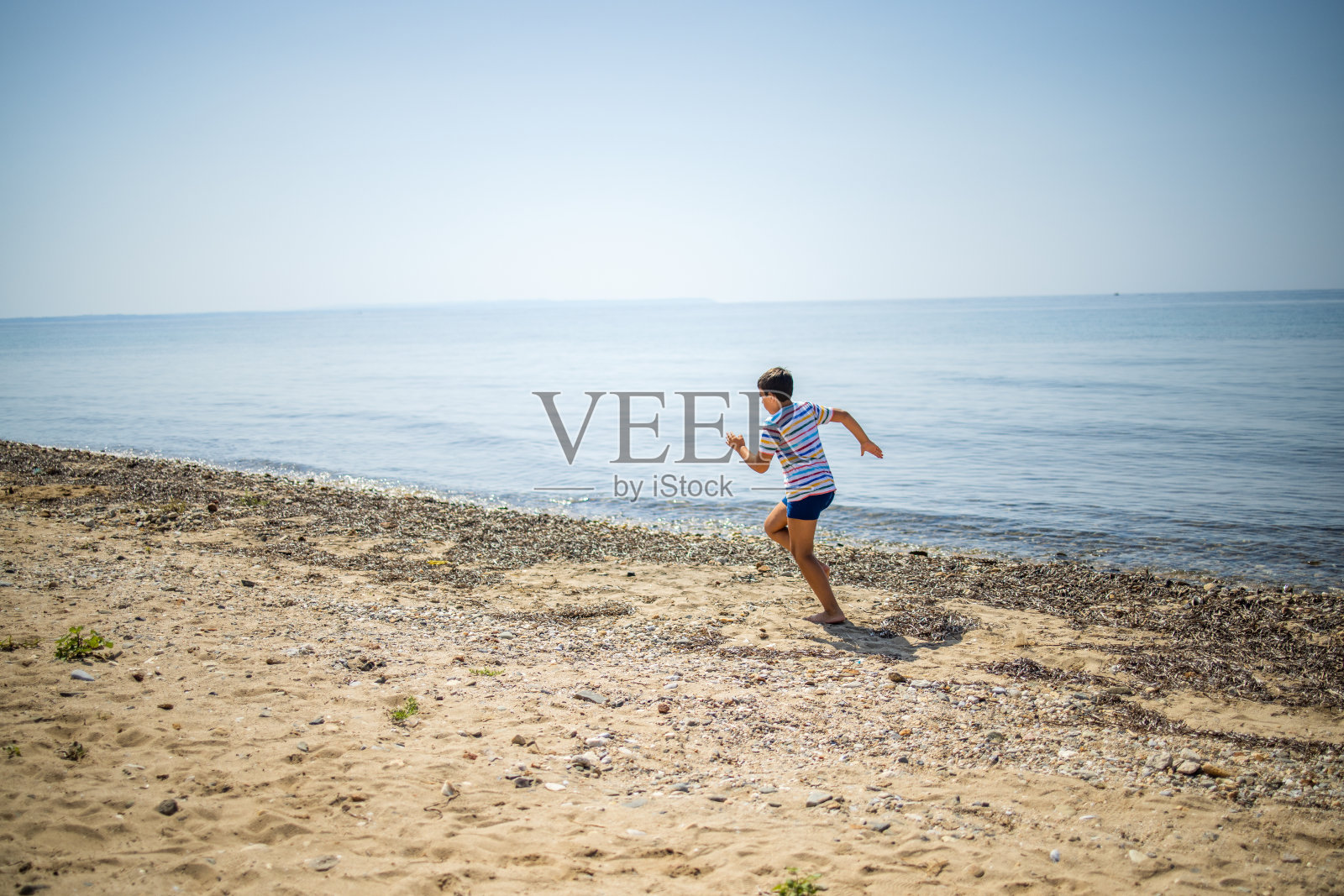 无忧无虑的白人男孩在沙滩上奔跑照片摄影图片