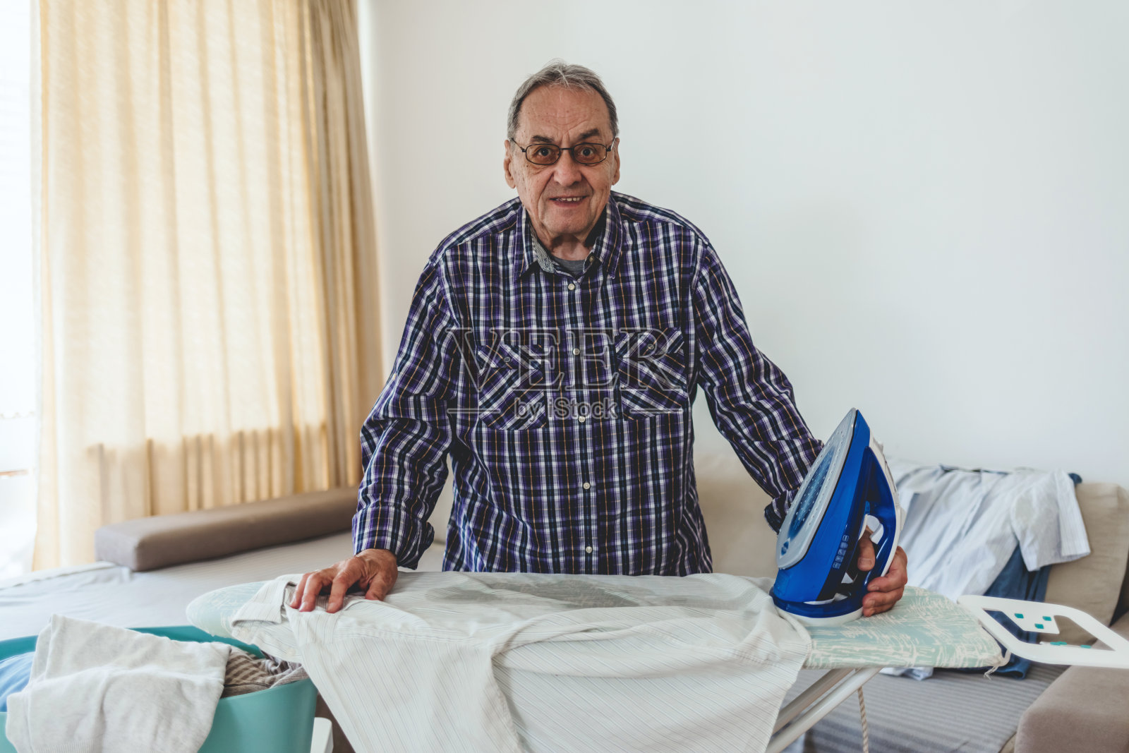 老人白天在家熨衬衫。老人在家熨衣服。照片摄影图片