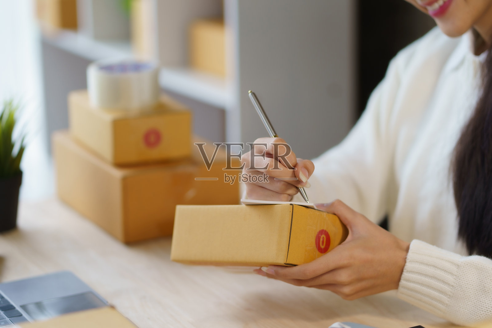 一名年轻女子的特写，她拥有一家在线企业，正在用笔记本电脑包装和检查余额，以获取准确的订单信息。照片摄影图片