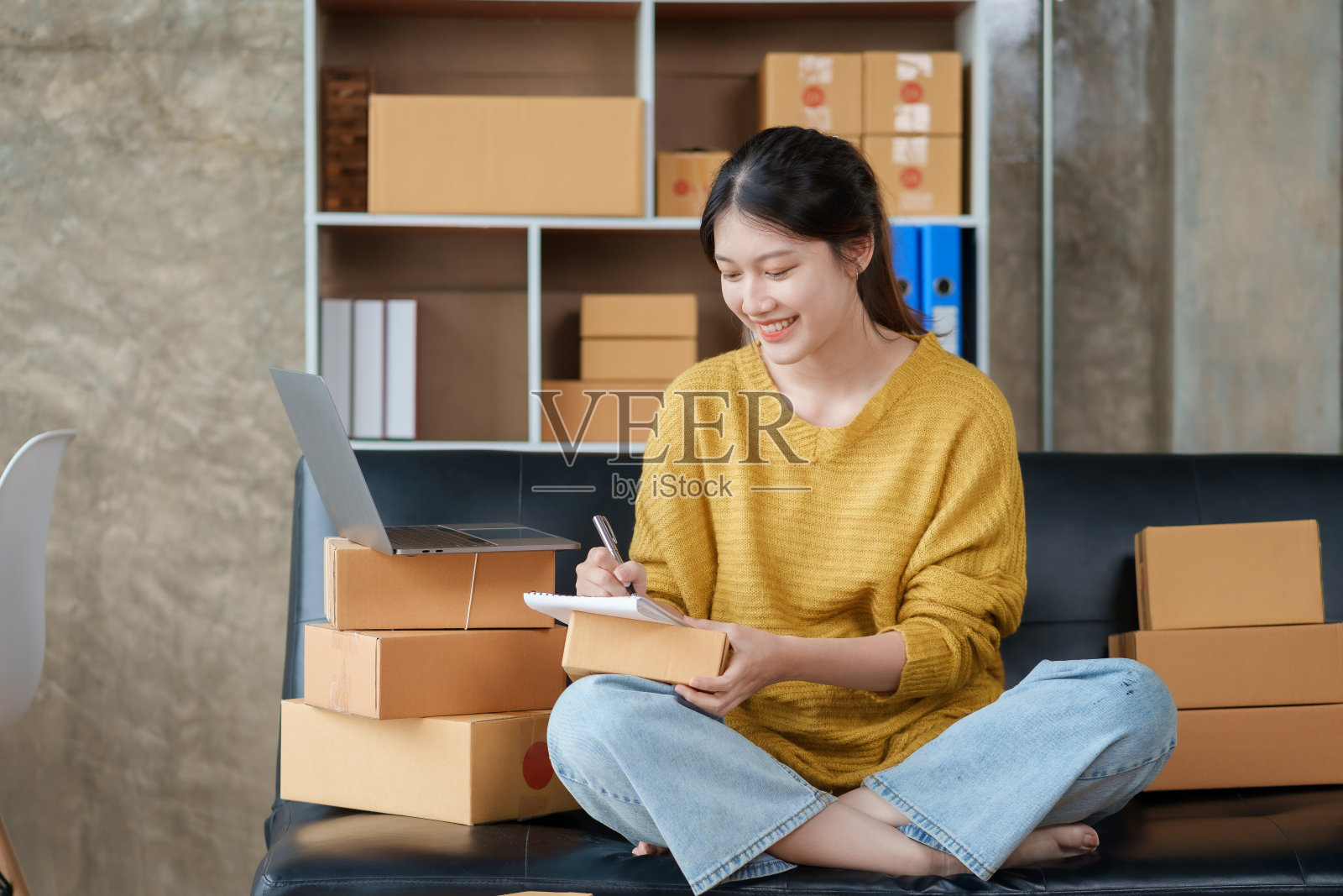 美丽亚洲网企业主正在准备一个包裹盒，准备将包裹送到客户手中。检查物品清单，收货地址是否正确。照片摄影图片