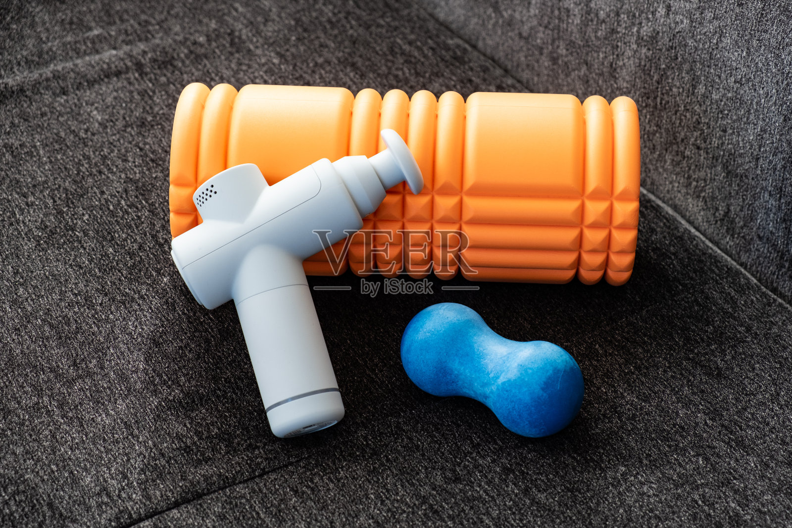 瑜伽垫上的肌肉按摩枪和滚筒照片摄影图片