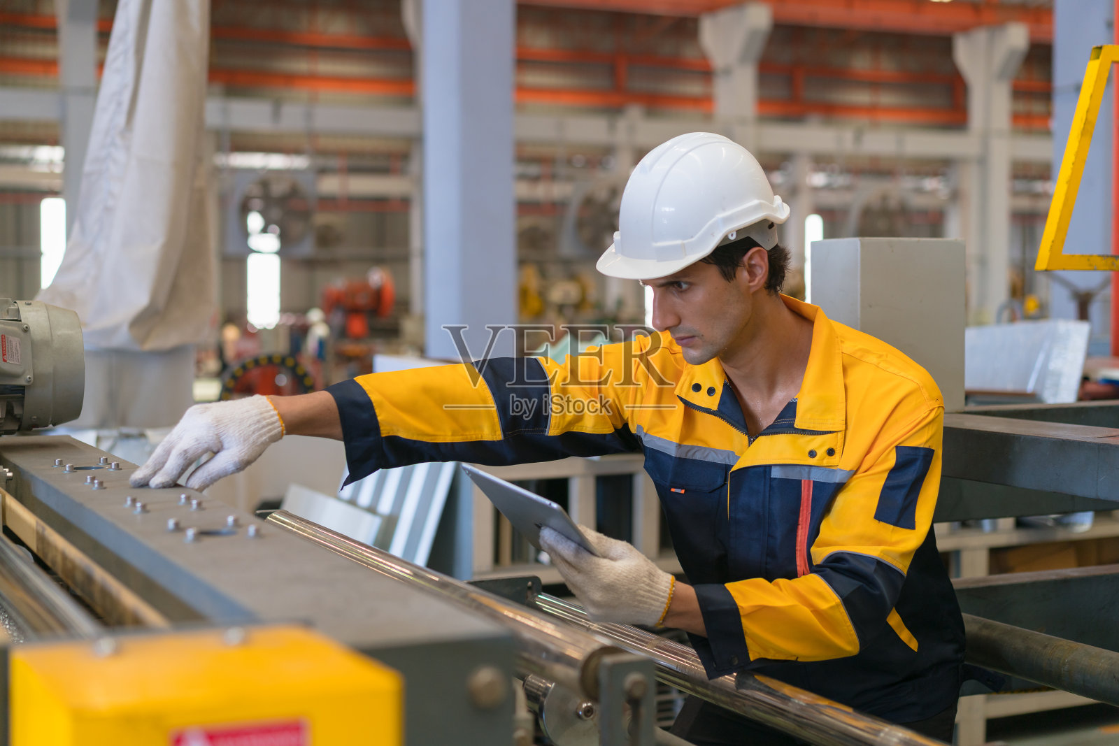 在金属制造仓库中穿着安全制服的专业重工业工程师，以安全第一的理念进行维修服务检查。照片摄影图片