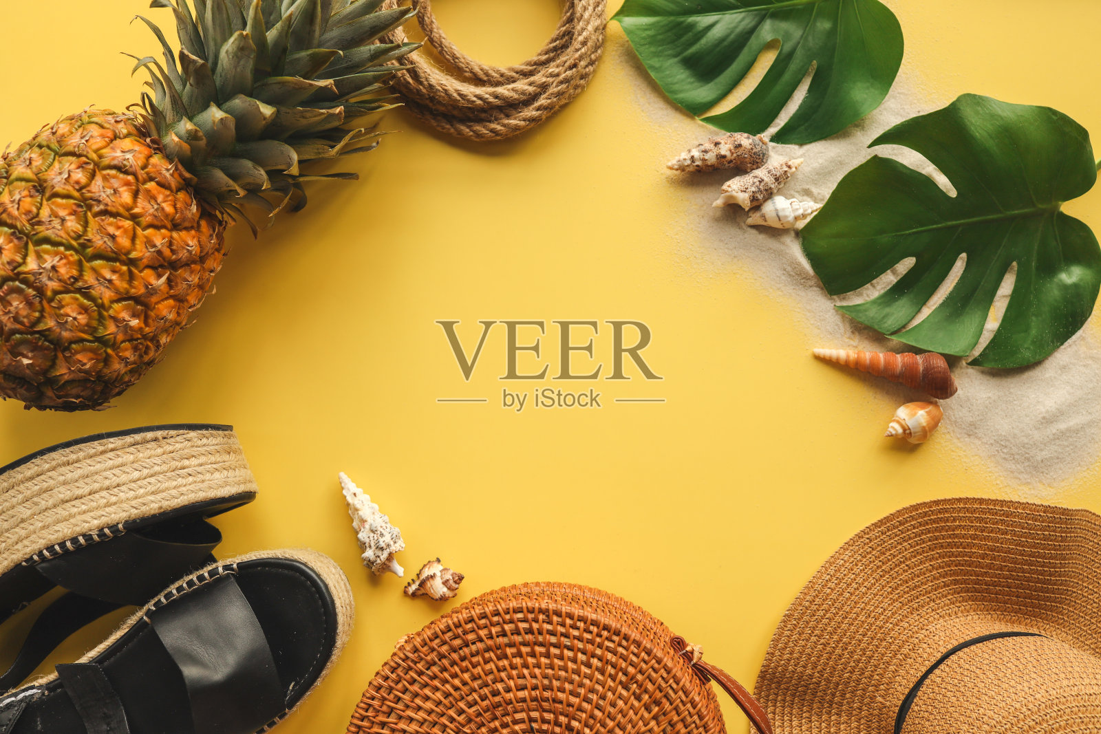五彩缤纷的夏季女性时尚装平铺。草帽，柳条鞋，黄色背景上的菠萝，俯视图，宽构图。夏季时尚，度假理念照片摄影图片