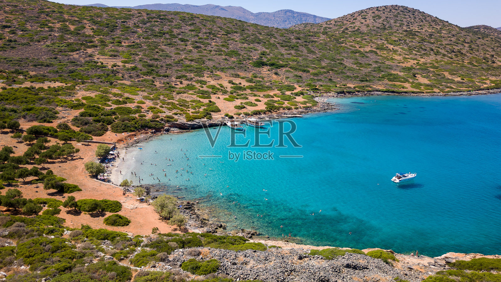 克里特岛(Kolokitha)炎热的夏日里，游泳者在一个小海滩和清澈的海洋上鸟瞰。照片摄影图片