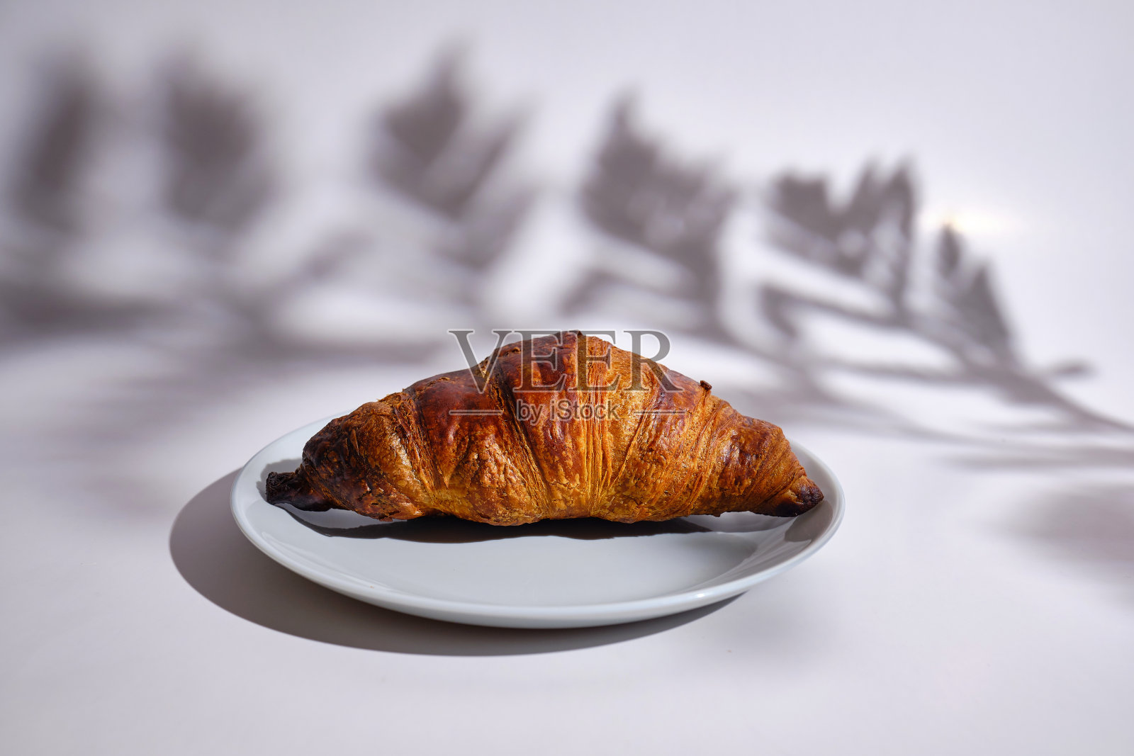 白盘子上的酥脆羊角面包准备好了。新鲜的自制蛋糕。美味的传统法式酥脆羊角面包作为早餐照片摄影图片