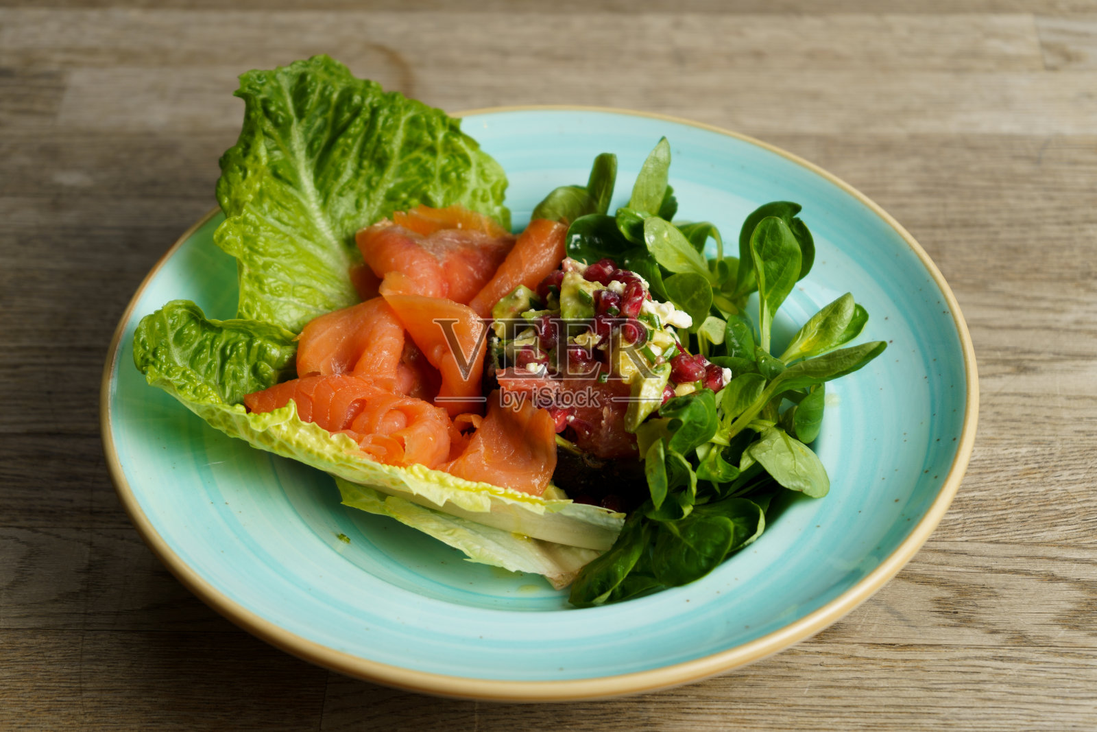 在木桌上的盘子里放着熏鲑鱼和鳄梨沙拉照片摄影图片