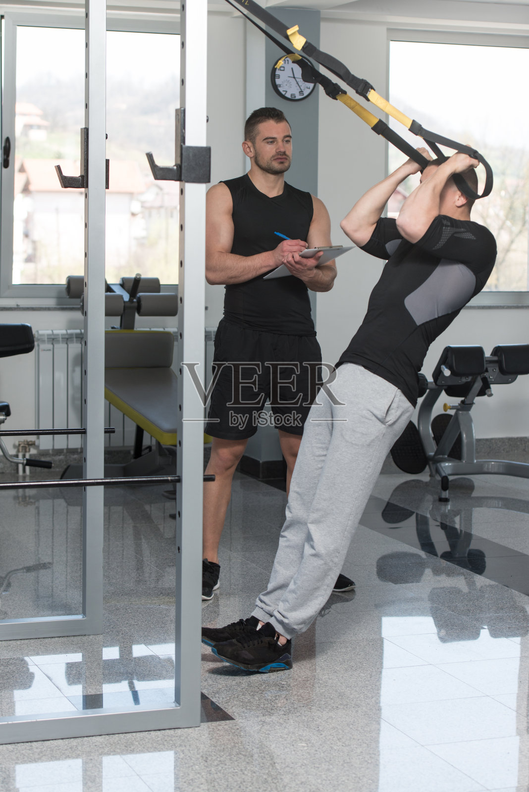 教练与剪贴板男子对Trx健身绑带照片摄影图片