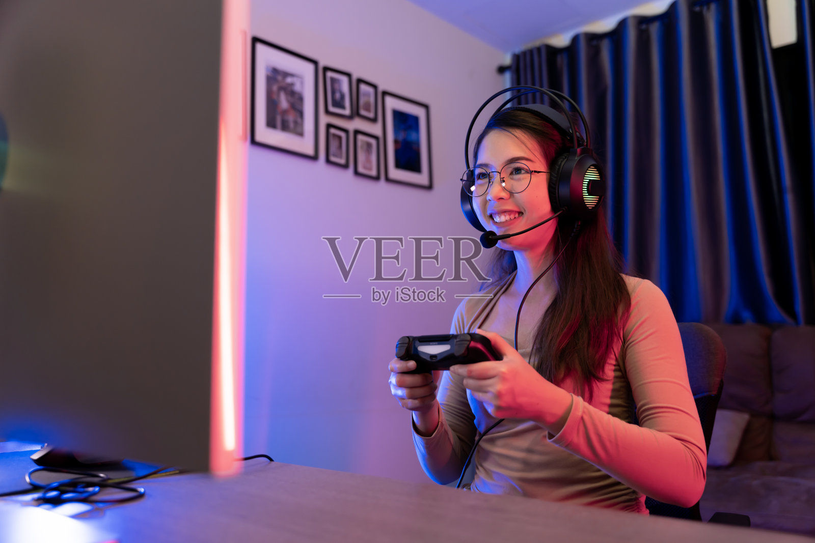 亚洲现代女性玩家在rgb照明的游戏室内玩游戏。照片摄影图片