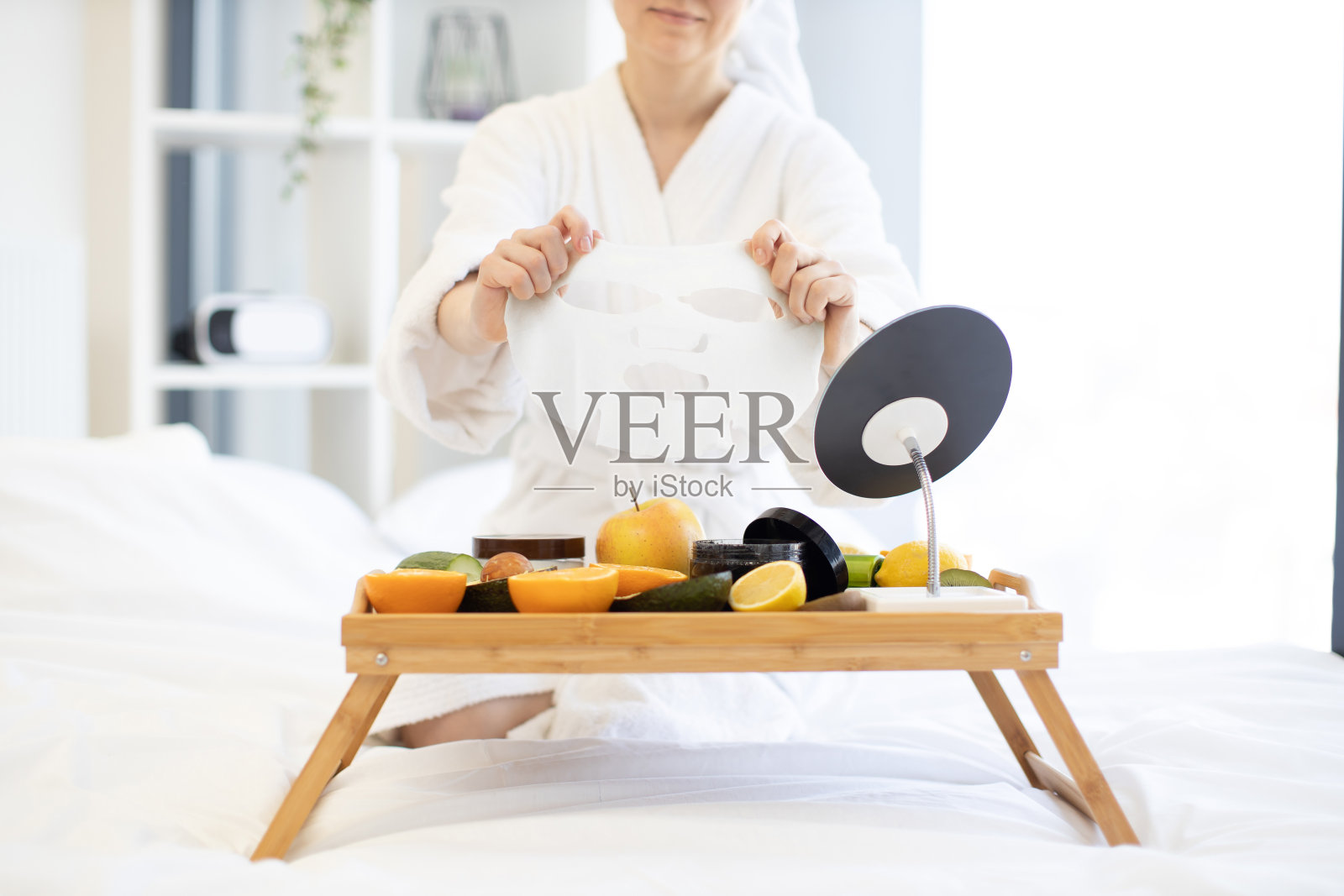 女士将面膜放在托盘上的水果和化妆品上照片摄影图片