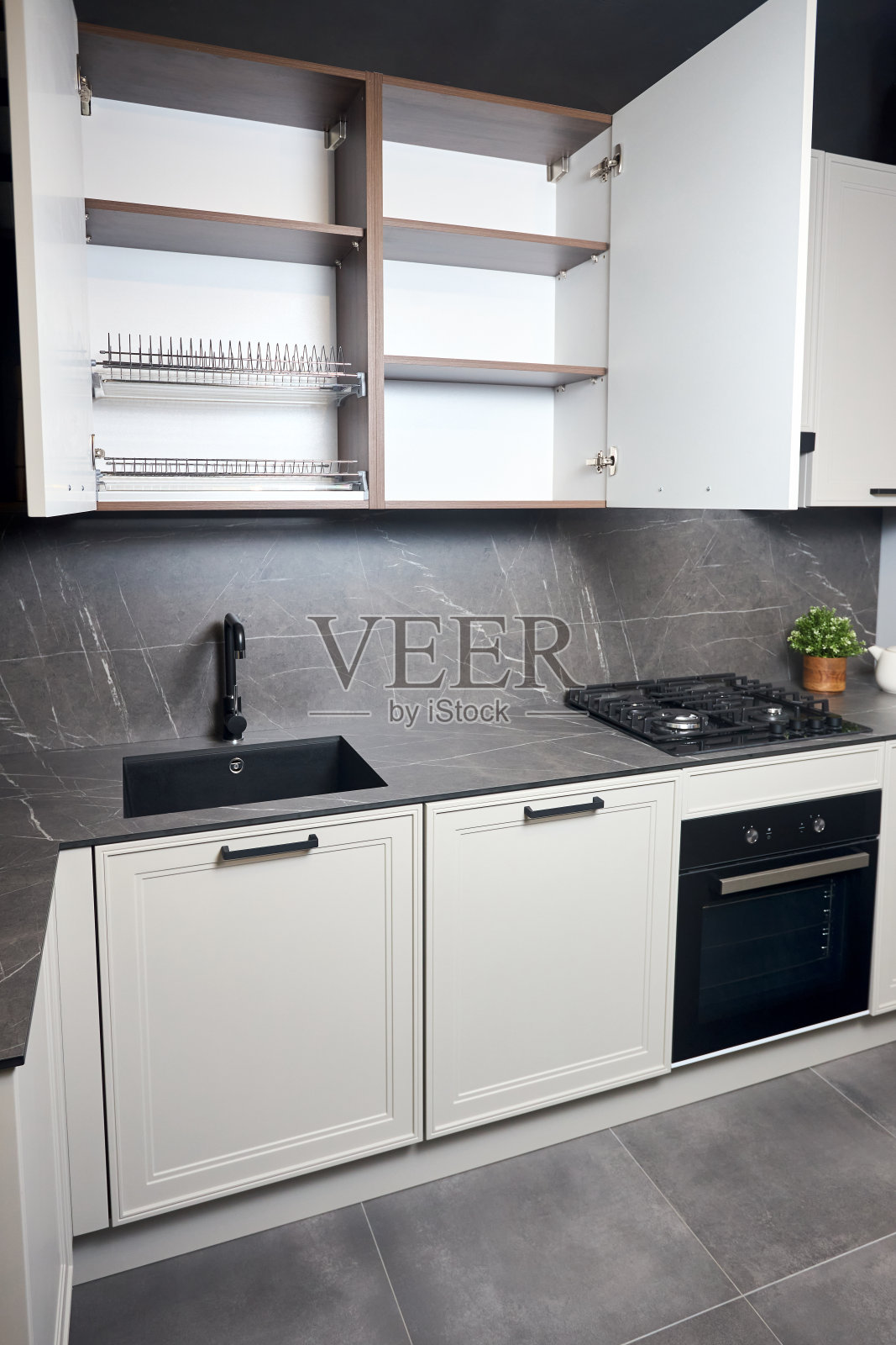 室内白色和灰色的厨房，水平线性布局。豪华现代安装的平面设计厨房，开放式橱柜货架，餐具柜与盘子干燥柜垂直拍摄。照片摄影图片