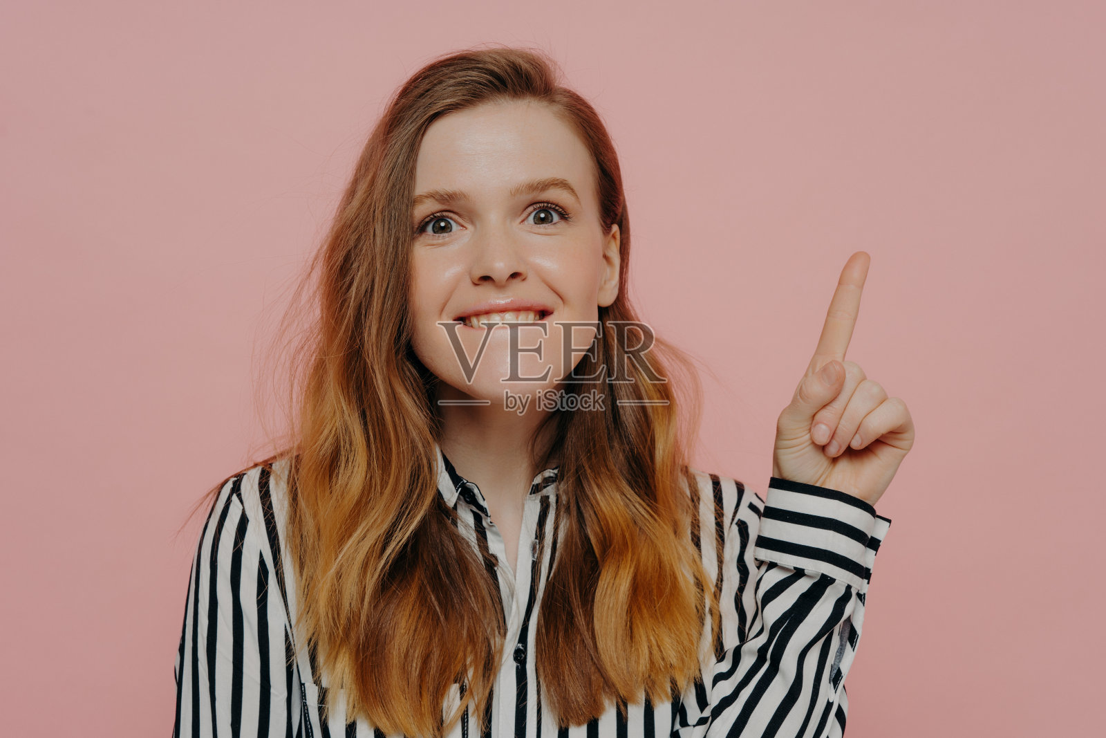 年轻兴奋的女人咬着嘴唇，指着上面的复印空间照片摄影图片