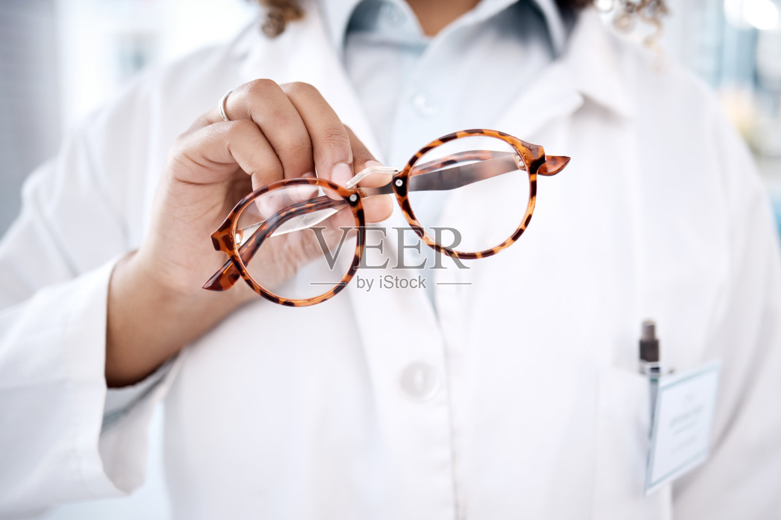 眼镜、手和视力，一位女医生在诊所里拿着一副镜框眼镜进行视力矫正。保健、医疗和保险，由一名女验光师出示处方镜片照片摄影图片