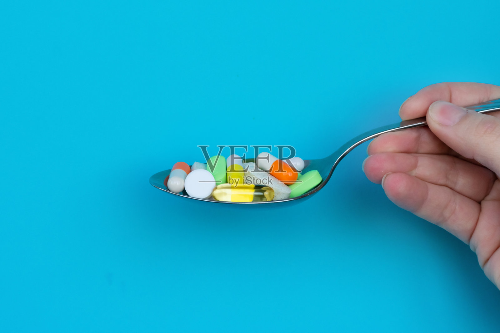 许多五颜六色的医药片剂、药丸和胶囊在勺子。过量用药，保健，膳食补充剂和抑郁症的概念。照片摄影图片