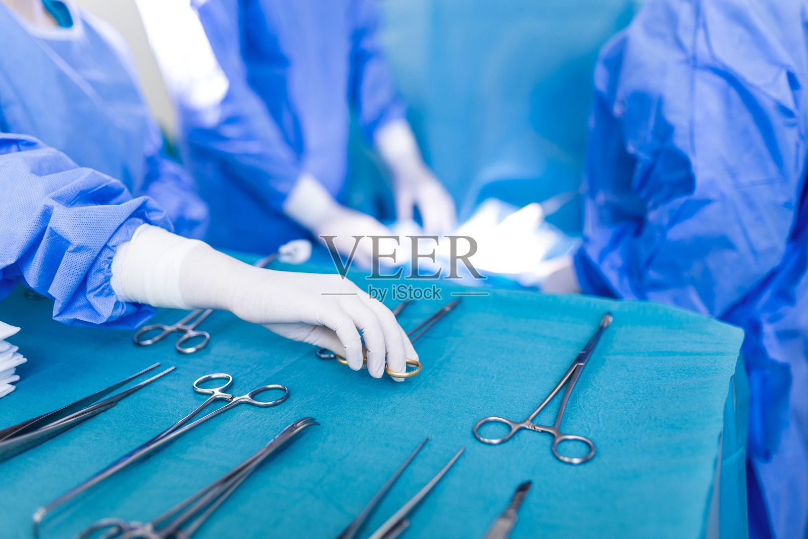 手术室背景手术病人，护士为外科医生组手拿手术器械。钢制医疗器械随时可用。外科和急救概念照片摄影图片