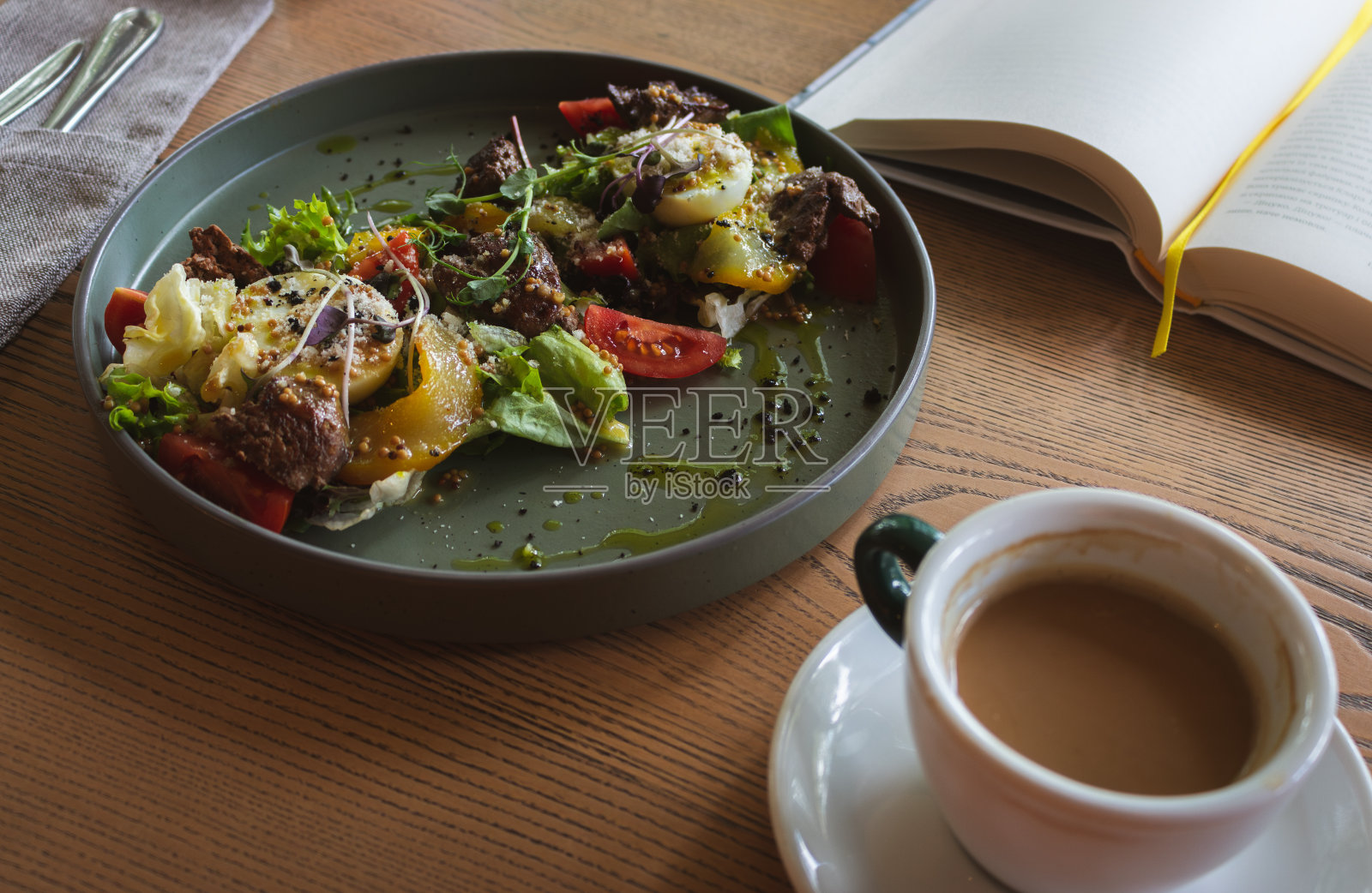 用咖啡杯和打开的书做沙拉。带书签的书和健康晚餐。平静的早餐概念。读书和吃饭。在咖啡馆吃晚餐。大城市的生活方式。照片摄影图片
