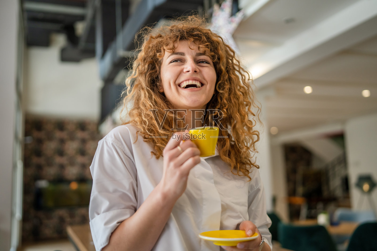 女子成年白种人女性开心地笑着在咖啡馆端着一杯咖啡照片摄影图片
