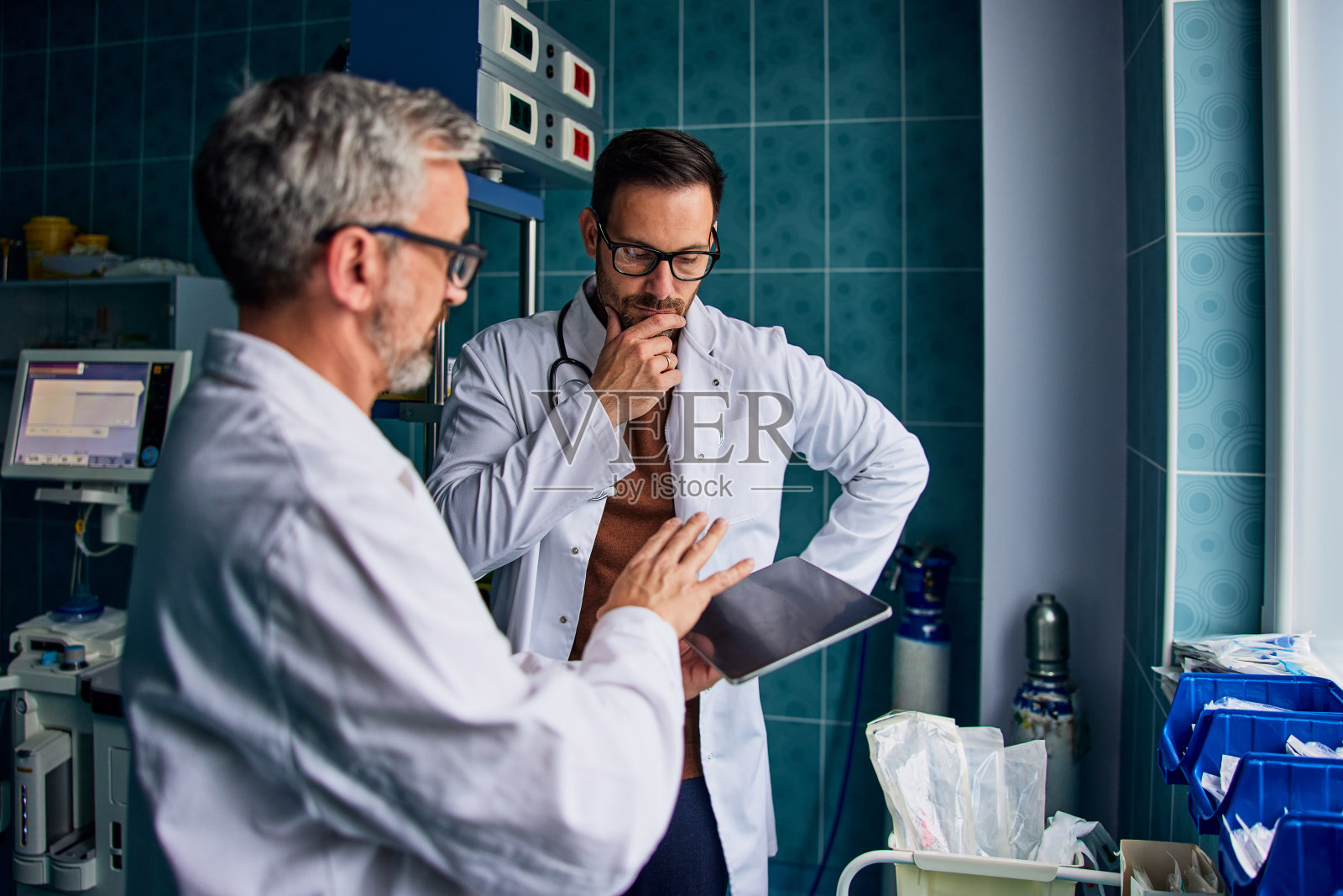 一位体贴的男医生和他的男同事站在一起使用药片。照片摄影图片