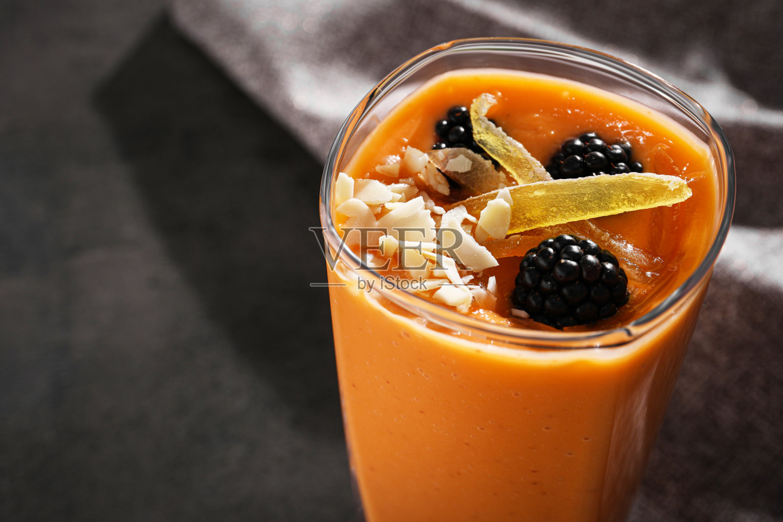 一杯美味的冰沙，配上黑莓、芒果糖和杏仁，放在灰色的桌子上，特写。文本空间照片摄影图片