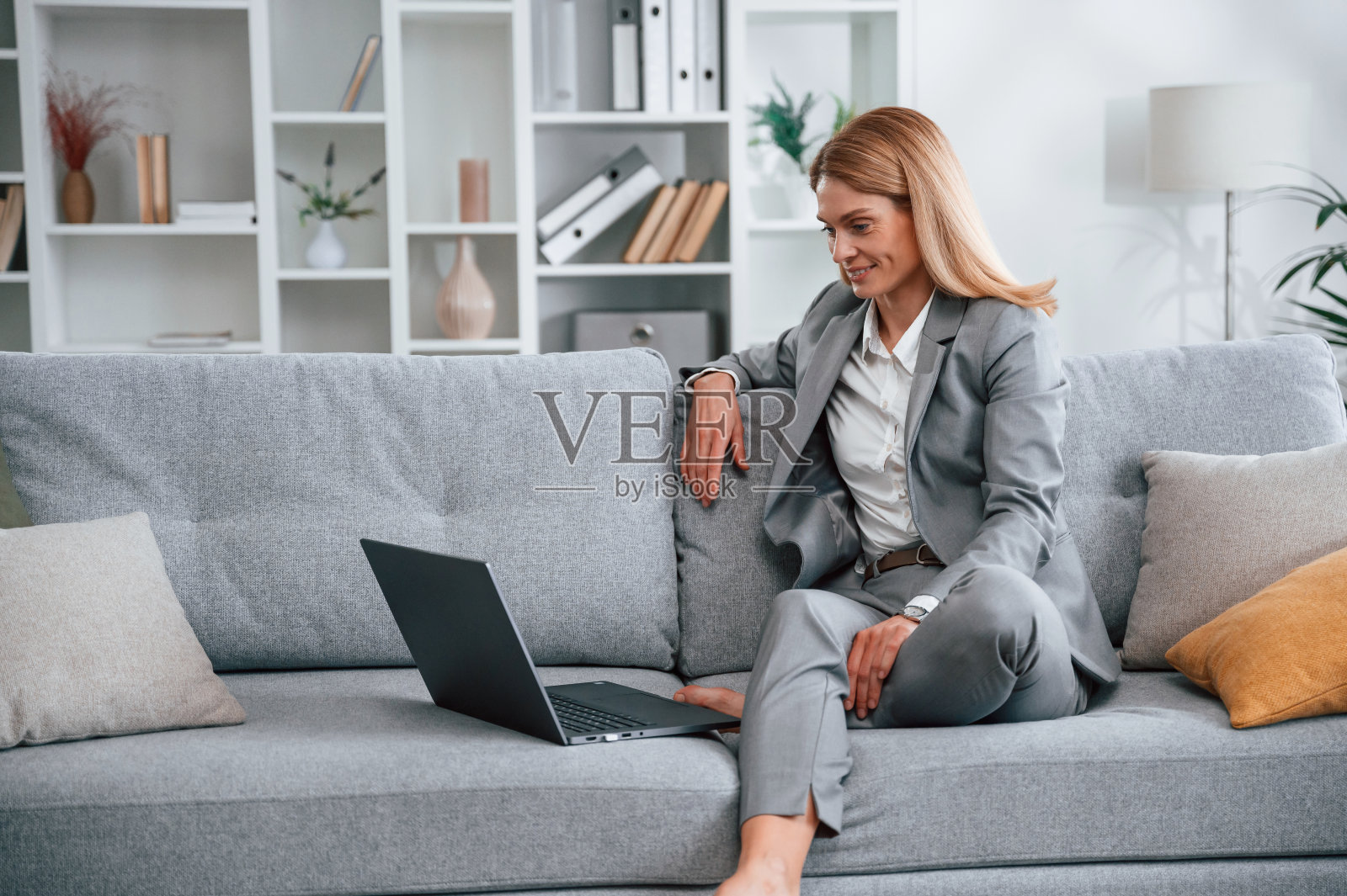 穿正装的女人在家，坐在沙发上照片摄影图片