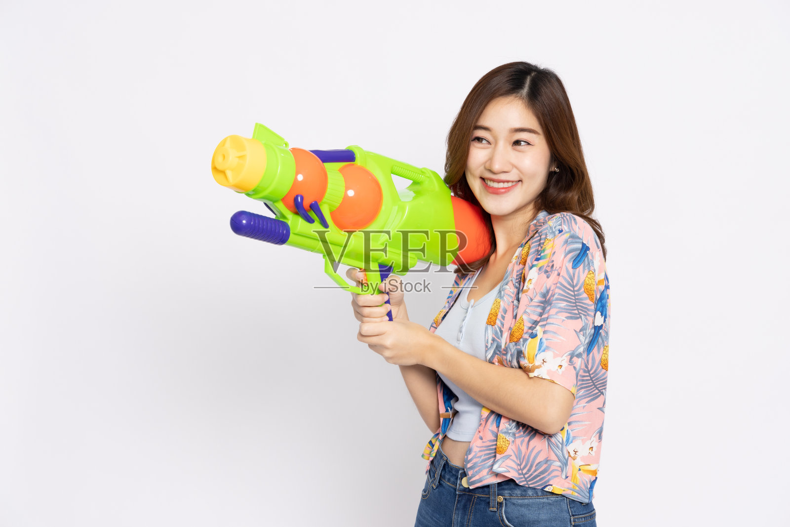 在泰国的宋干节上，年轻的亚洲女子身穿夏季服装，手持塑料水枪，在白色的背景中孤立无援照片摄影图片