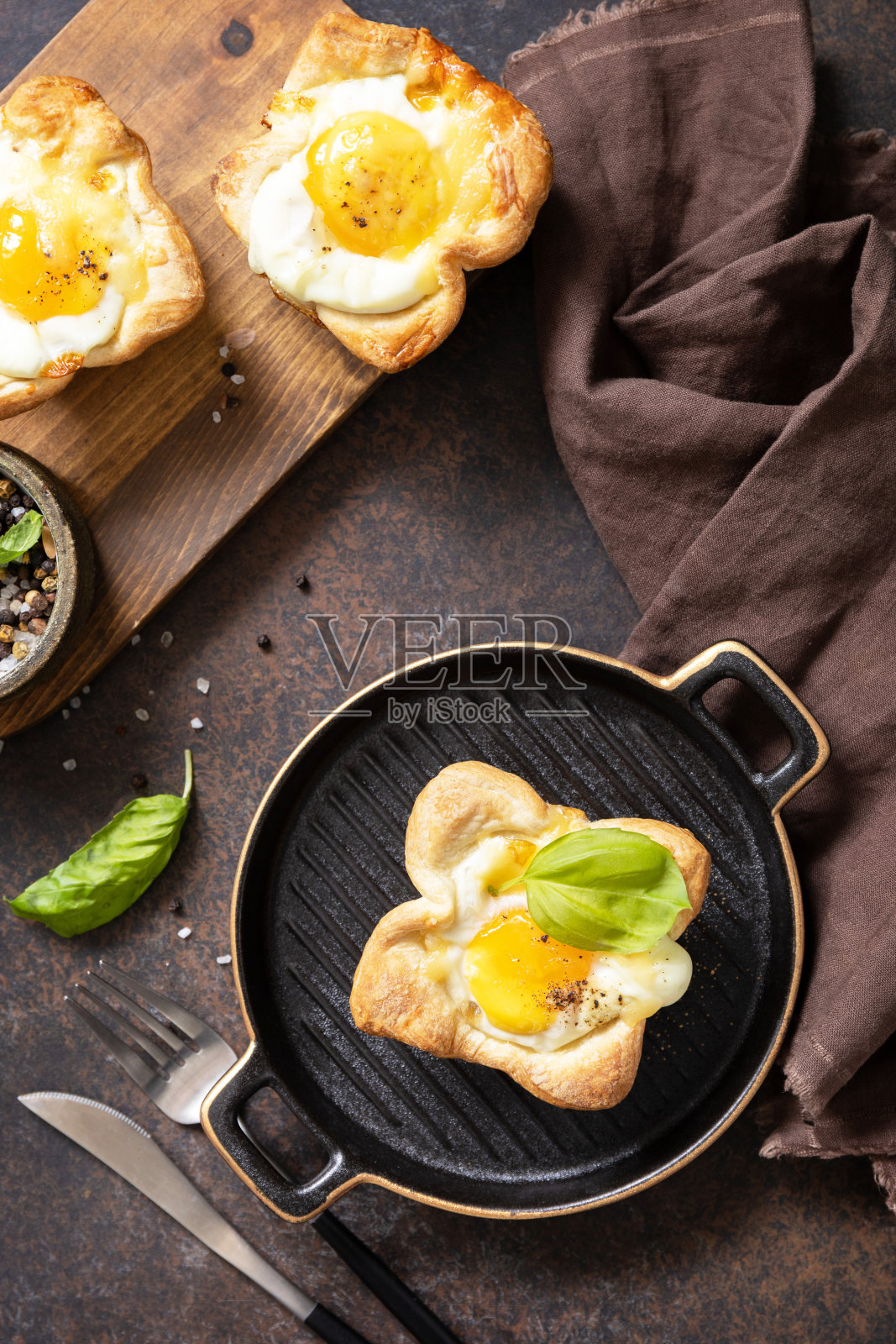 酥皮炒鸡蛋配上奶酪和培根，放在石盘上。早餐的想法，零食。从上面看。照片摄影图片
