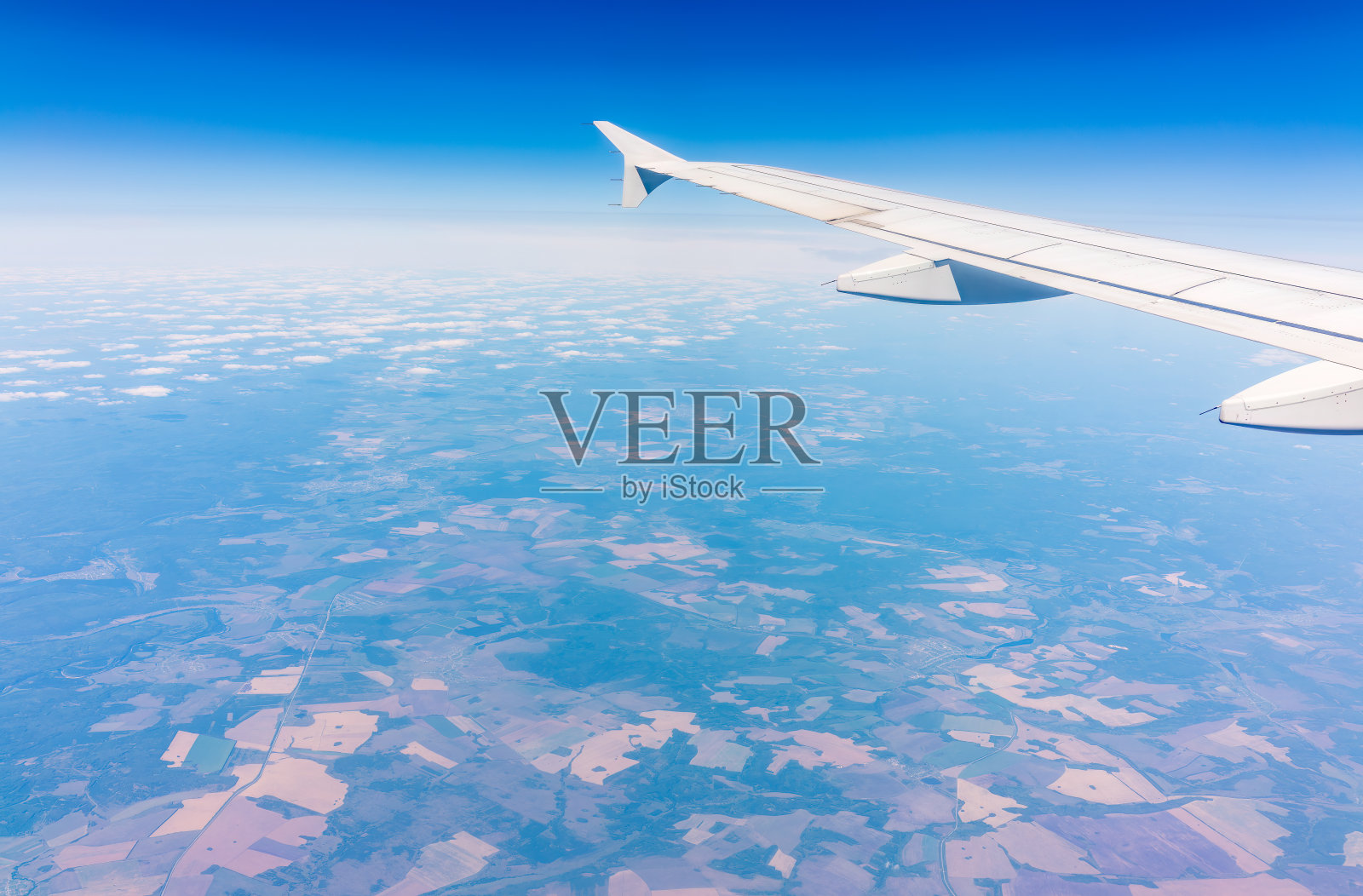 从飞机窗口俯瞰绿色地面。从飞机窗口看到日出时美丽的云照片摄影图片