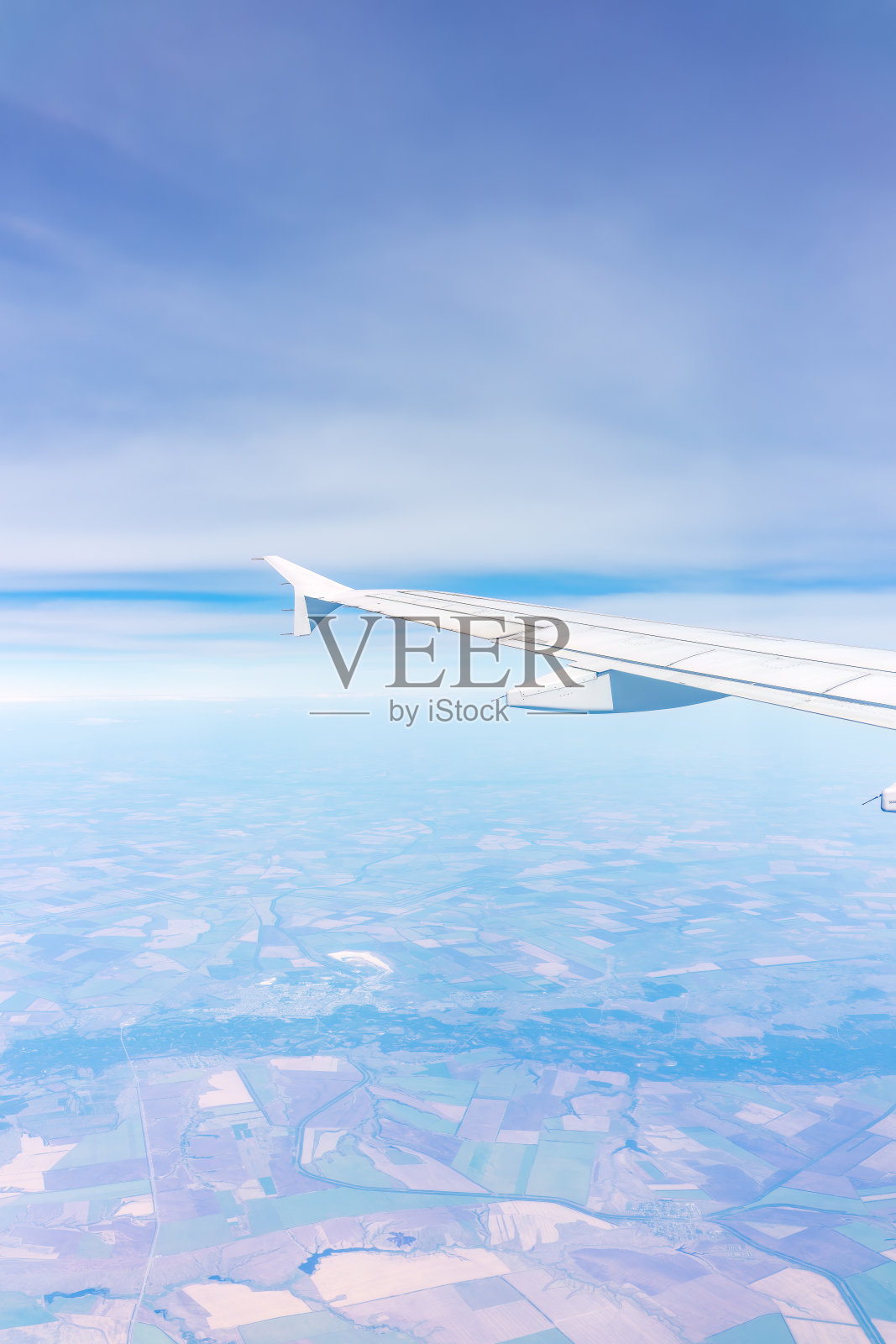 从飞机窗口俯瞰绿色地面。从飞机窗口看到日出时美丽的云照片摄影图片