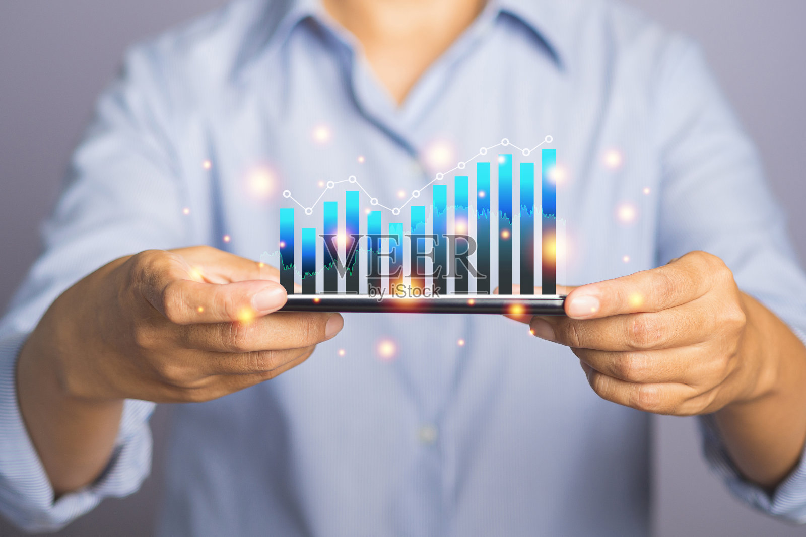 商人手持手机，在虚拟屏幕上显示统计图表。照片摄影图片