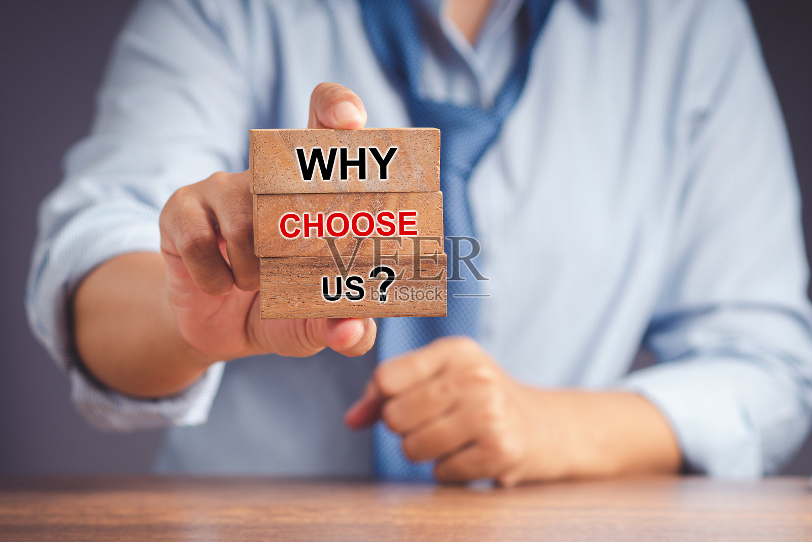 一个商人的手拿着木块，上面写着为什么选择我们，业务，战略和服务理念照片摄影图片