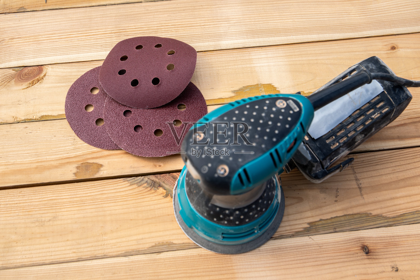 圆形砂纸盘和轨道砂光机。木制背景照片摄影图片