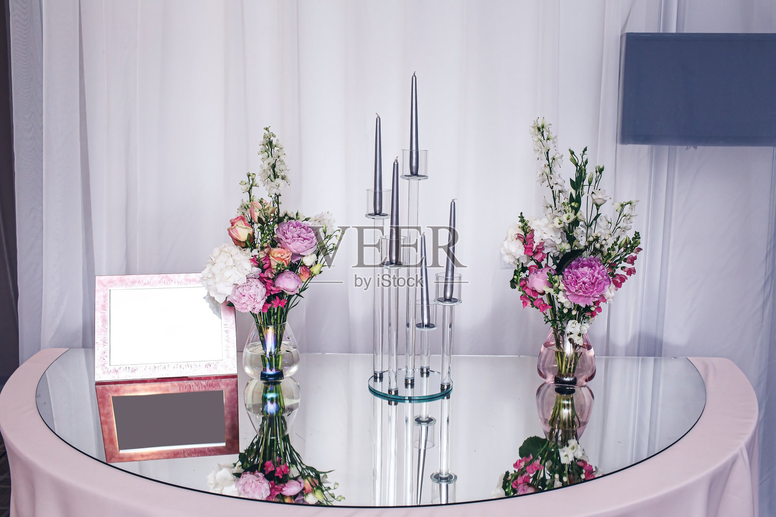 邀请桌装饰。镜子桌，鲜花，蜡烛和空白框架照片摄影图片