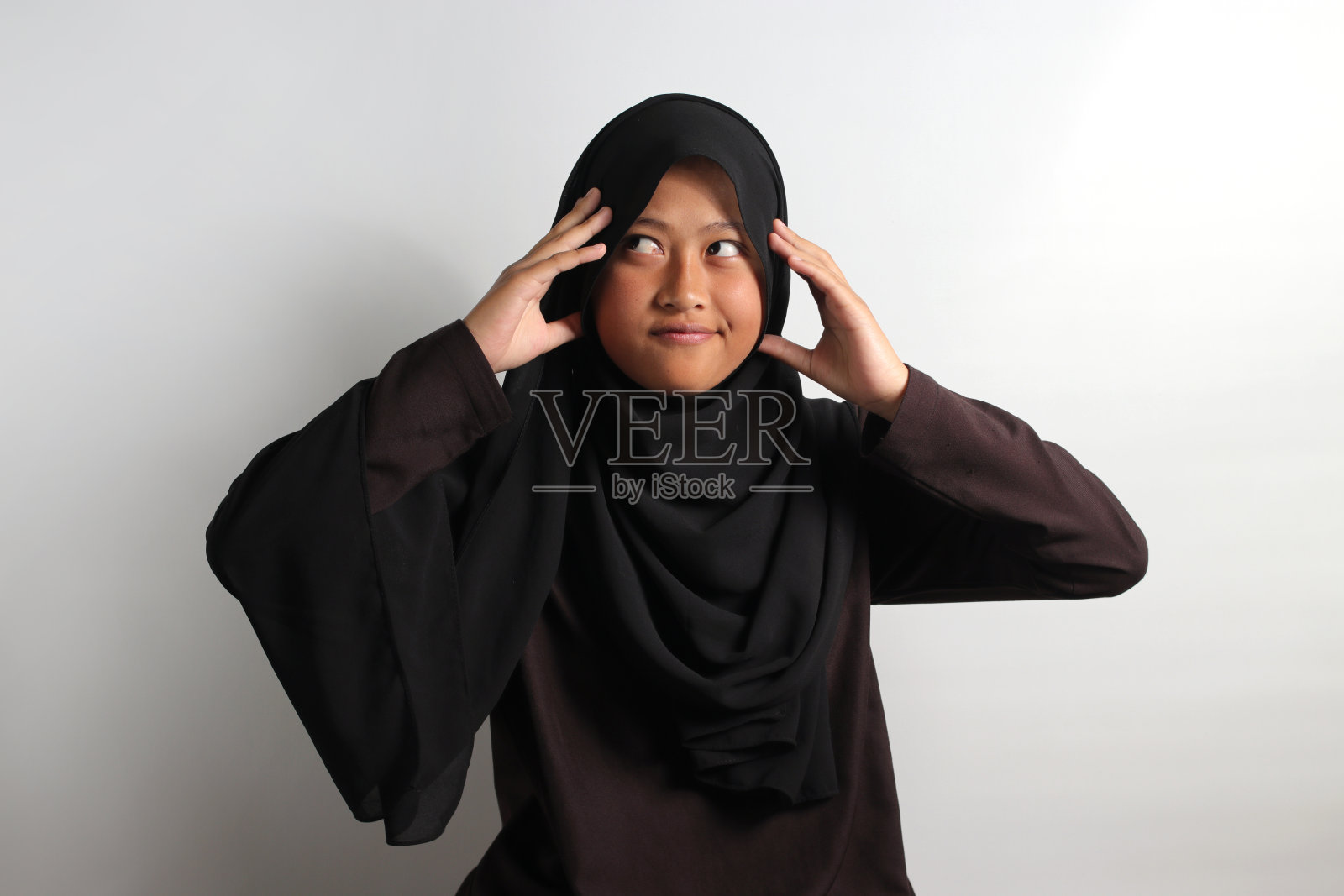 戴头巾的年轻亚裔女孩捂着头照片摄影图片