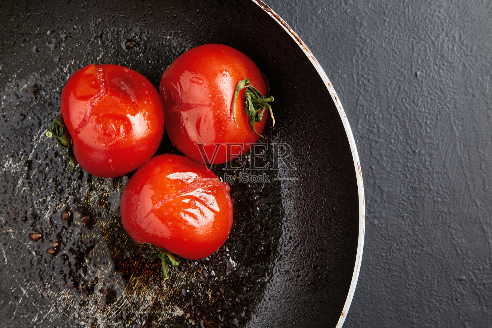 在黑色的混凝土背景上用黑色的煎锅烤西红柿照片摄影图片