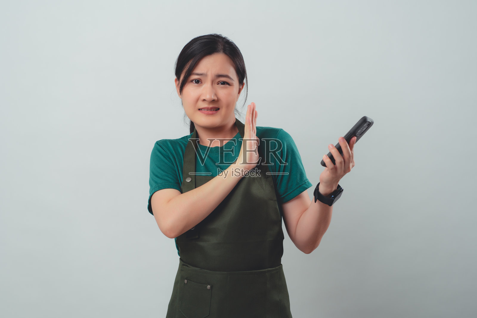 身穿围裙的亚洲女性在智能手机上与顾客发生冲突照片摄影图片