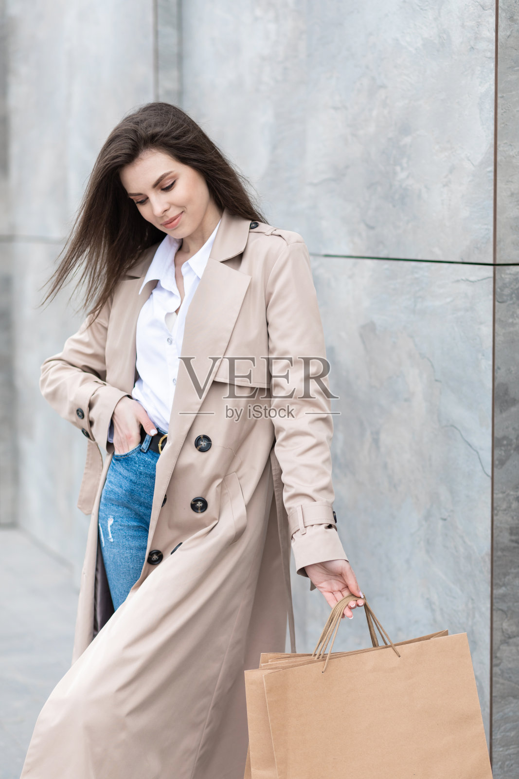 在购物中心附近，一个穿着休闲衣服的女孩拿着购物袋和很多东西，微笑着递给你她的包裹，消费主义销售和人的概念照片摄影图片