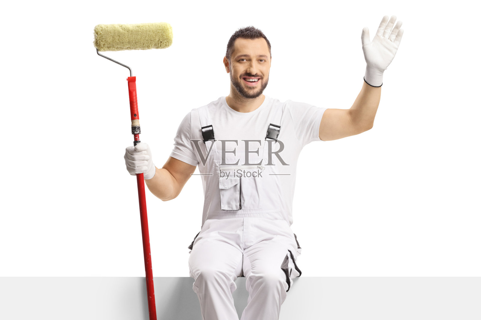 油漆工拿着油漆滚筒坐在空白板上挥动照片摄影图片