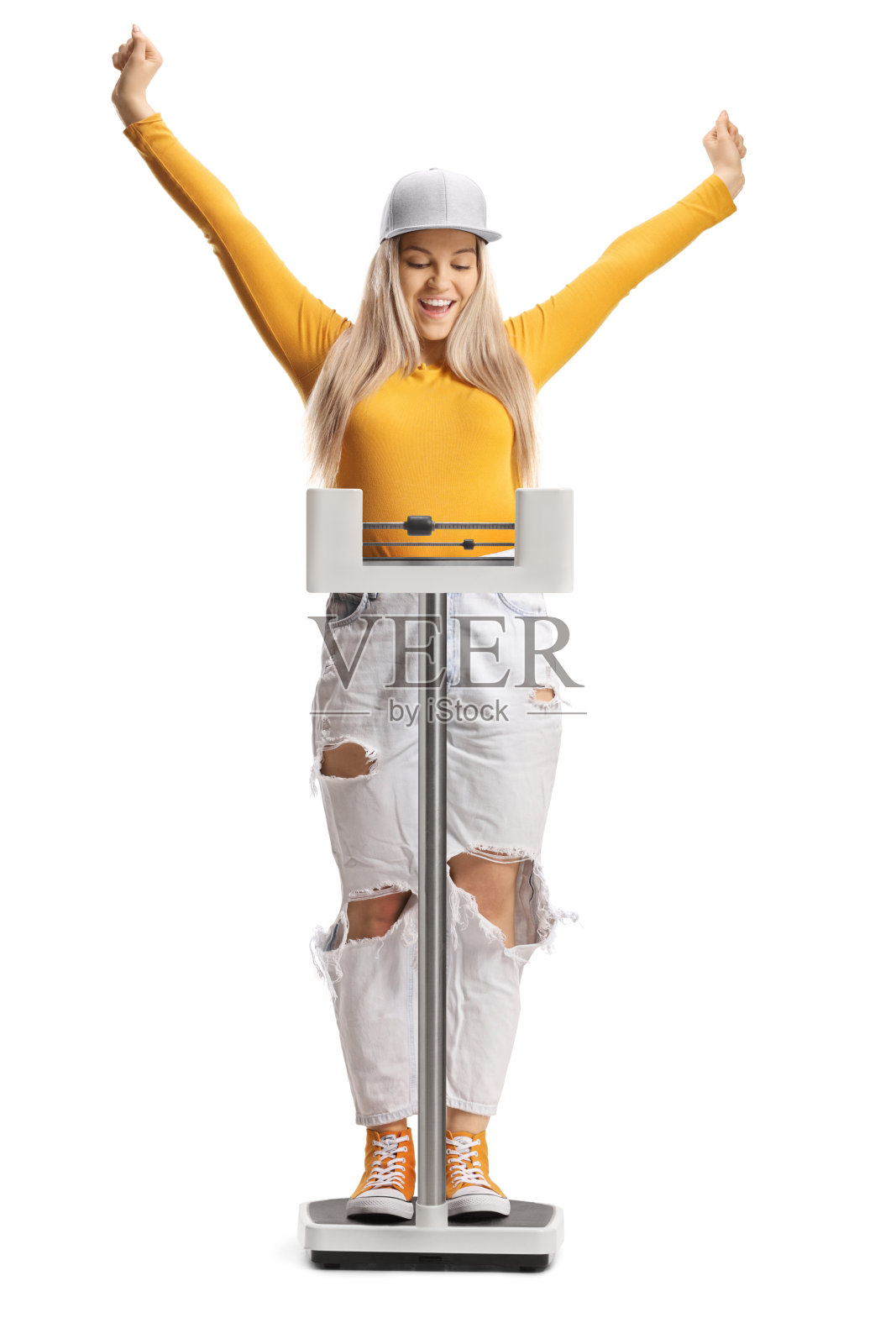 年轻的女性在减肥后庆祝，她站在白色背景的天平上照片摄影图片